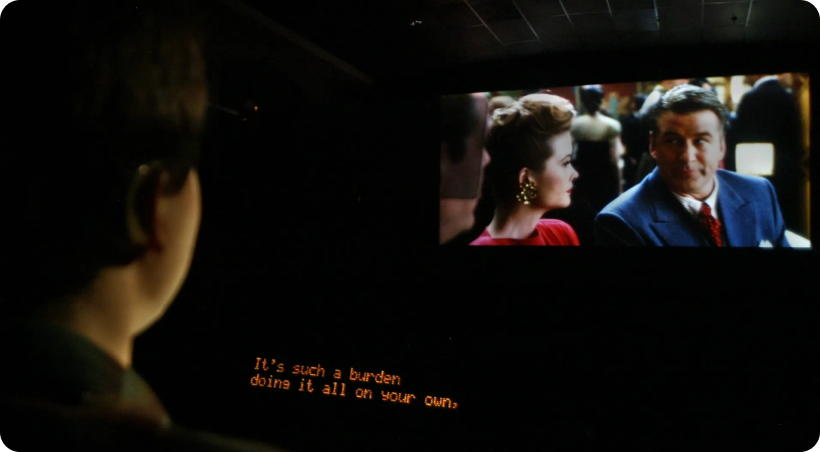 Moviegoer watching a film with captions shown on a seat-mounted closed caption device